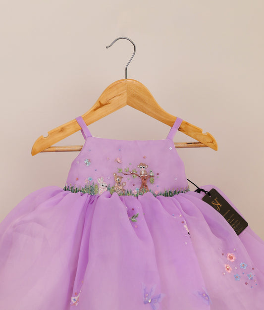 Close view of an lavender plain organza jungle-themed birthday frock against plain background