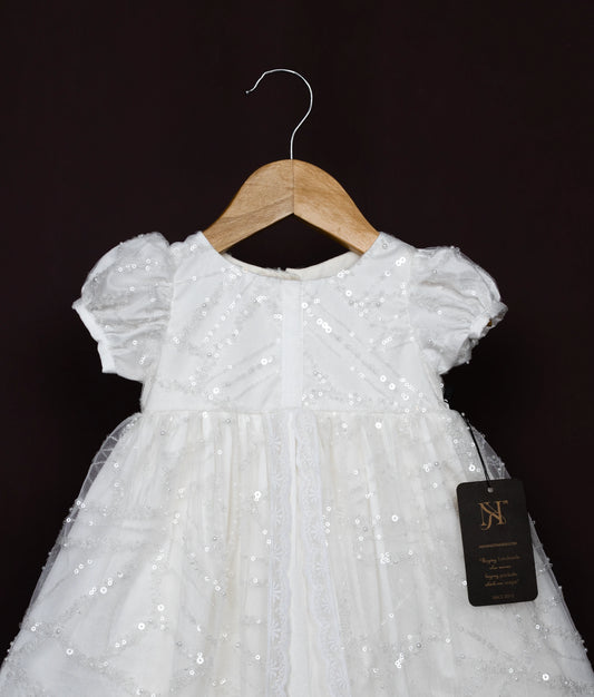 Close view of a off-white sequin dress on a hanger with a dark background.