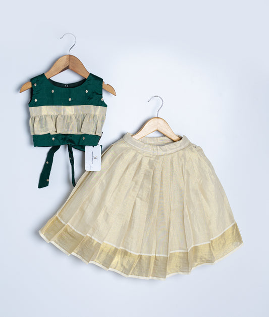 A green semi-silk top with a kasav full-length skirt for a baby girl, displayed on wooden hangers against a white background.