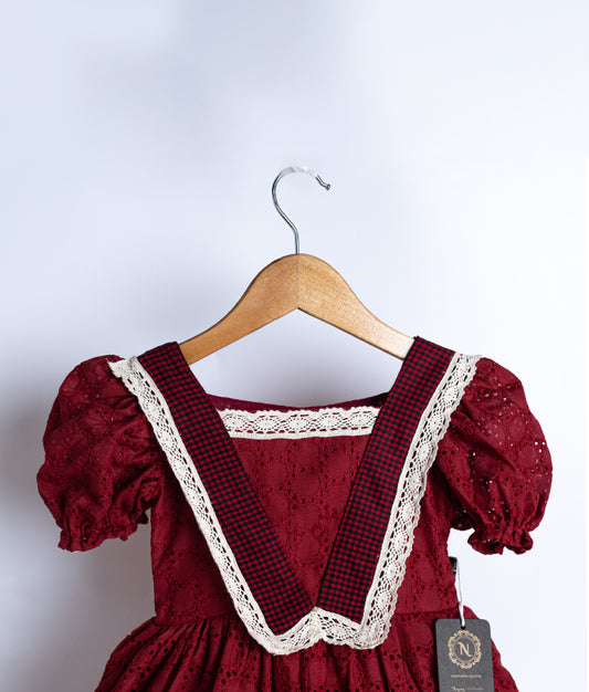 Close view of an maroon colored frock displayed on hanger.