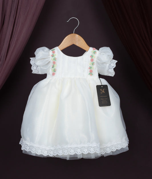 Off-white baby girl dress with floral embroidery, puff sleeves, and lace hem on a hanger.