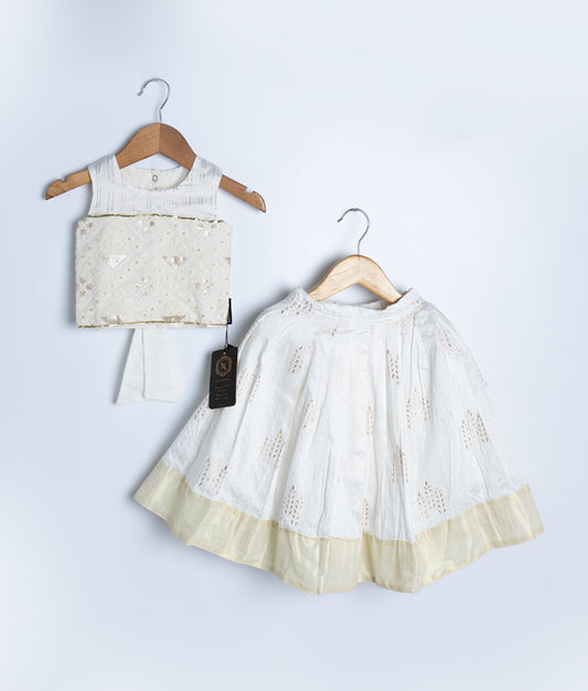 Traditional white kids’ ethnic outfit featuring a sleeveless embroidered blouse with delicate embellishments and a matching skirt with a soft yellow hem, displayed on wooden hangers against a light background.
