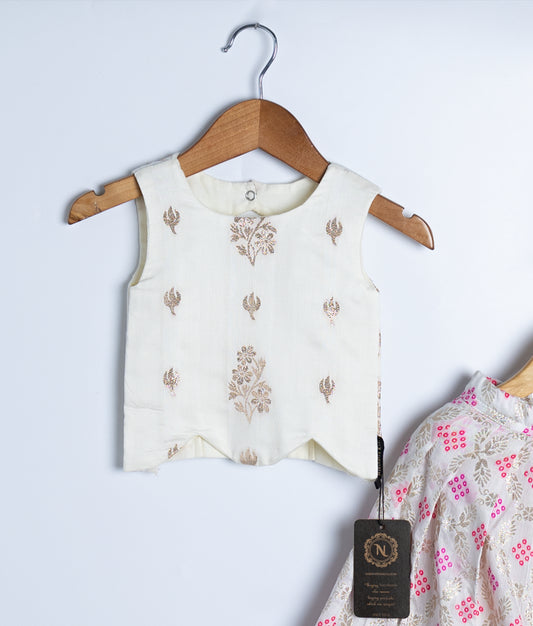 A kid's festive outfit with cream sleeveless printed top and matching cream skirt adorned with pink and gold floral patterns, displayed on hangers
