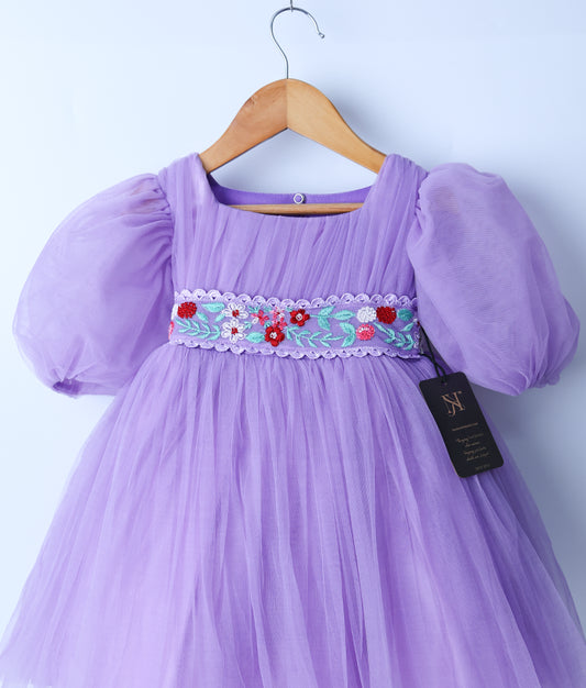 Close view of an lavender tulle net birthday frock displayed on a hanger.