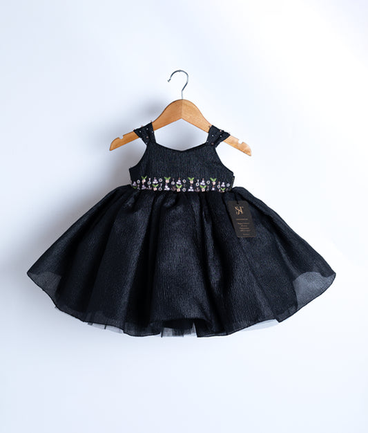 Front view of a black crush organza birthday frock for baby girls featuring floral waist embroidery and gem-decorated straps