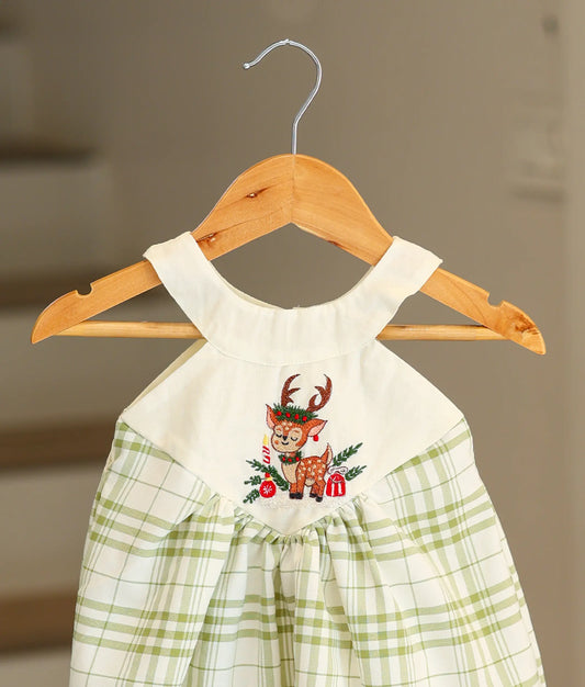 Close-up of the festive deer embroidery and the white cotton halter neck on the Christmas frock.