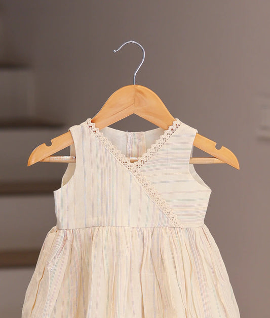 Close-up of the delicate cream lace trim and crossover neckline on the off-white striped cotton baby dress