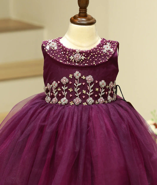Close-up of the intricate floral handwork with pearls, sequins, and beads on the one-piece cape collar of the purple frock.