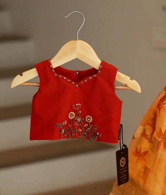 Close-up of the red top showing detailed golden floral handwork, sequins, and bead embroidery along the square V-neckline