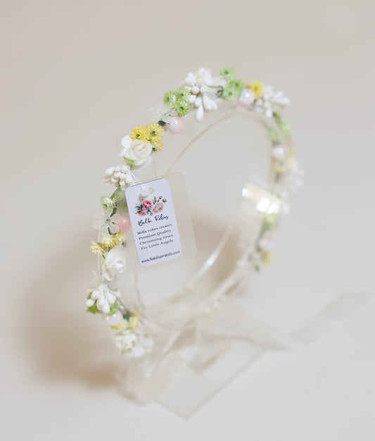 Close-up of the handmade tiara showing white roses, yellow blossoms, iridescent pearls, and green buds