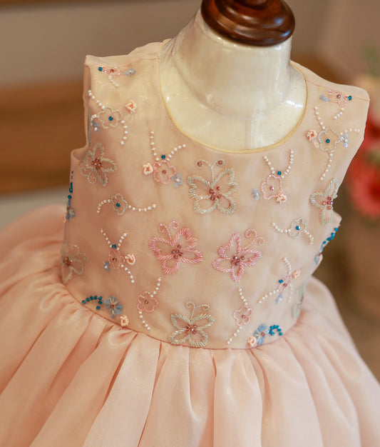Close-up of the golden frock bodice showing the intricate pastel floral and butterfly embroidery details