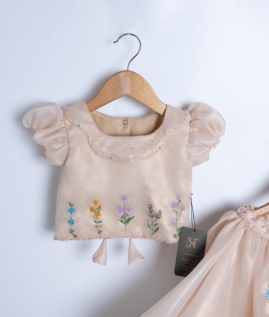 Close-up of the golden top showing the crystal-adorned Peter Pan collar and delicate pastel floral embroidery at the hem