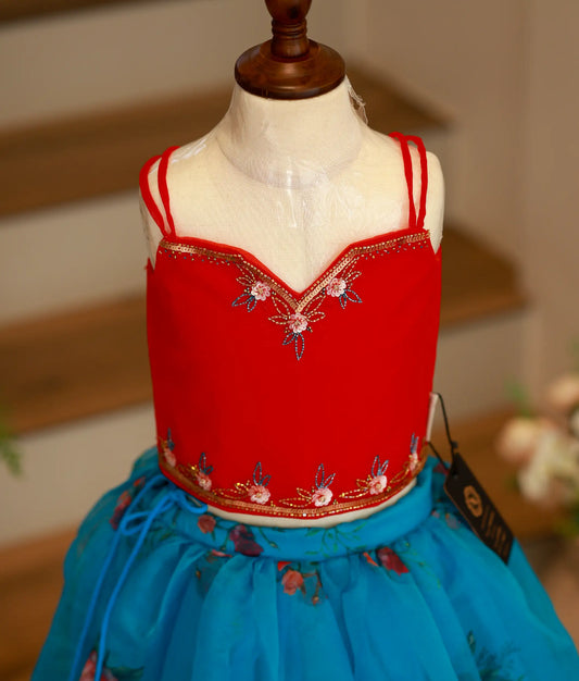Close-up of the red top showing the intricate floral handwork, sequins, and bead detailing along the neckline and hem