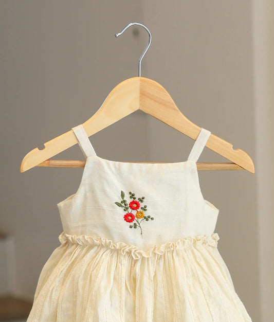 Close-up of the handcrafted floral bouquet embroidery and ruffled waist on the off-white Kasavu cotton dress
