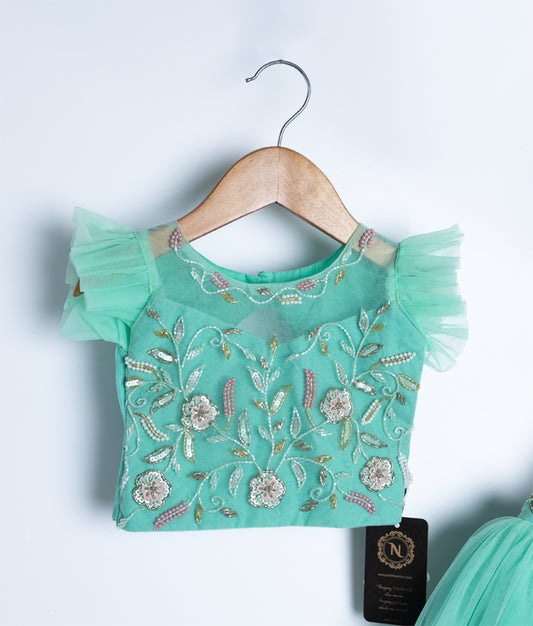 Close-up of mint green floral embroidered top of baby dress