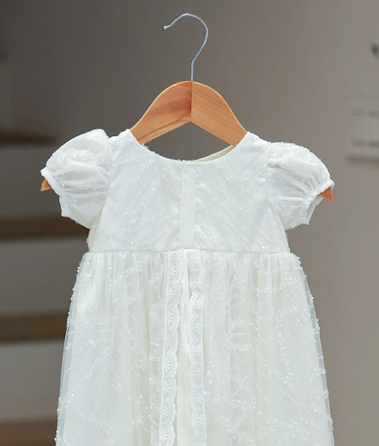 Close-up of the off-white baptism frock showing the intricate bodice work, puff sleeves, and elegant lace trim detailing.