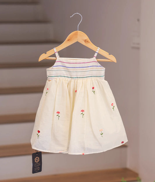 Front view of an off-white cotton frock for girls featuring small embroidered flowers and thin straps.