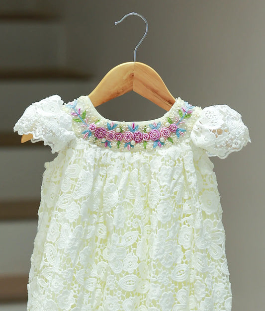 Close-up of the off-white baptism frock highlighting the handcrafted pink and purple floral bullion embroidery and pearl accents on the crochet bodice.