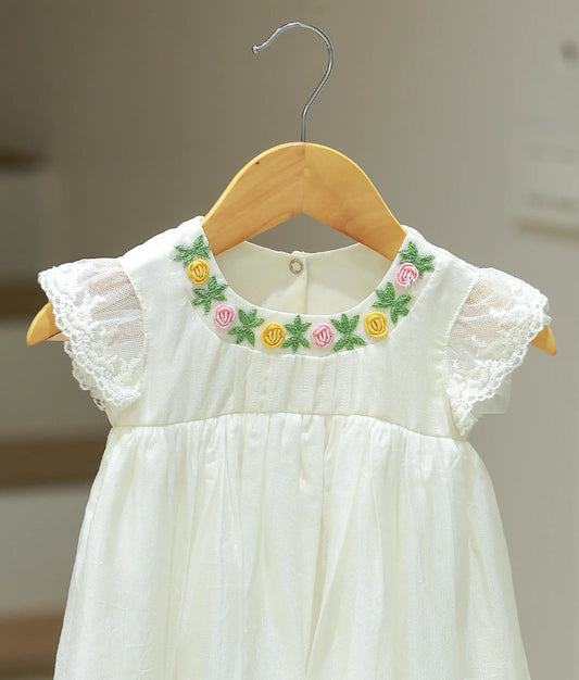 Close-up view of the off-white baptism frock highlighting the intricate floral embroidery patterns and fine threadwork.