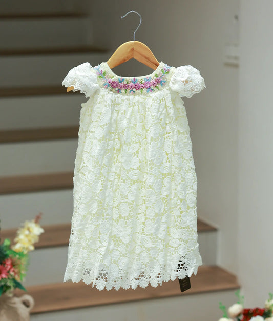 Full front view of a below-knee length off-white baptism frock for baby girls featuring an intricate crochet overlay and hand-embroidered neckline.