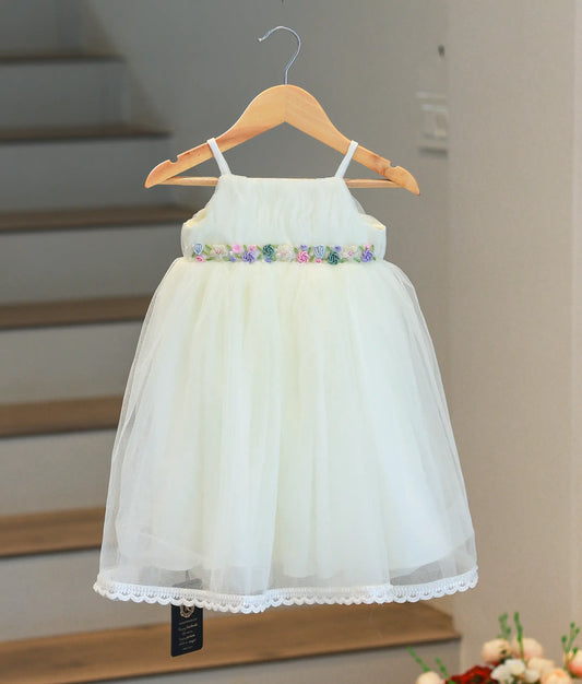 Front view of an off-white handworked tulle baptism gown with a floral waist belt and lace hem.