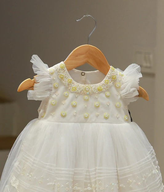 Close-up of the off-white baptism gown highlighting the intricate hand-worked embroidery and delicate bead detailing on the tulle fabric.