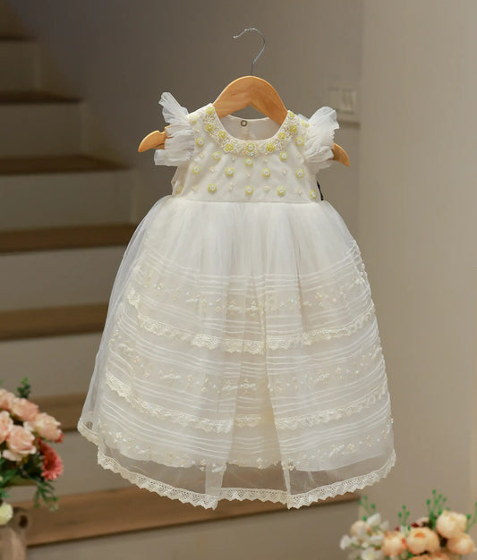 Full front view of an off-white baptism gown for baby girls featuring a hand-worked bodice and a long, flowing tulle net skirt.