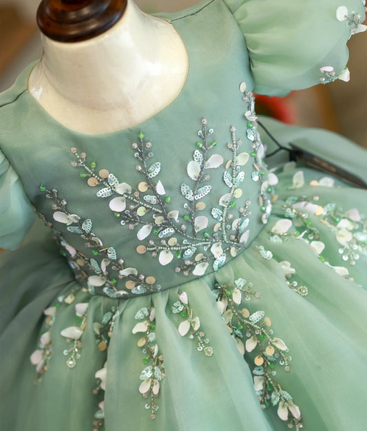 Close-up of the pastel green bodice showing intricate floral motifs and handworked balloon sleeves