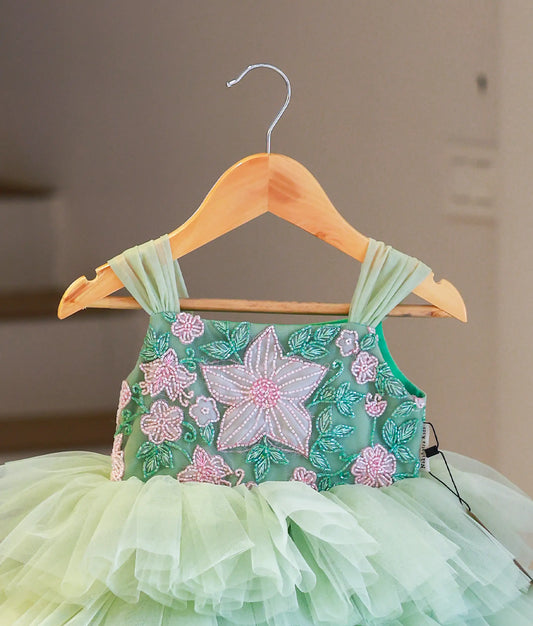 Close-up of the pastel green frock highlighting the intricate pink and white floral beadwork and pleated tulle straps.