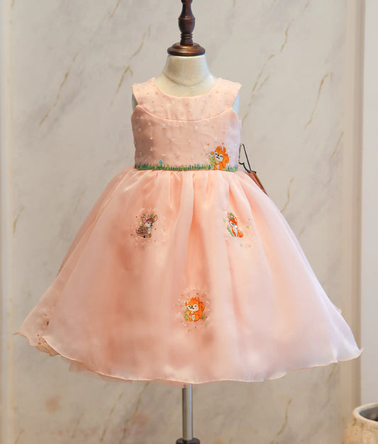 Front view of a pastel peach jungle theme birthday frock for girls featuring fox embroidery and a layered skirt