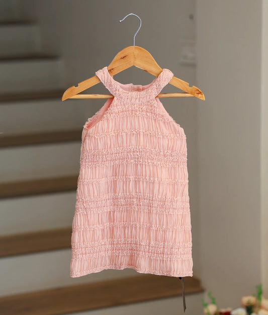 Front view of a peach georgette A-line birthday frock for baby girls featuring a tiered ruffle halter neck.