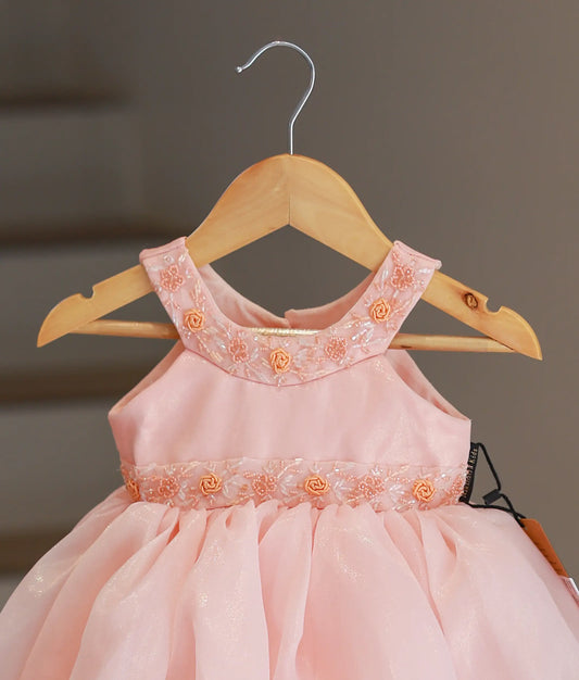 Close-up of the peach frock showing the hand-embroidered floral collar and the belt-style handwork on the yoke.
