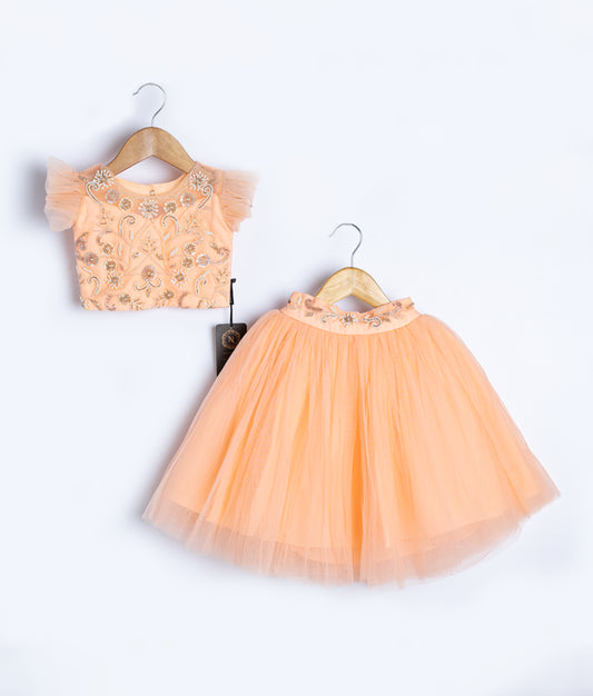 Peach baby girl outfit featuring star pattern top and matching tulle skirt for special occasions