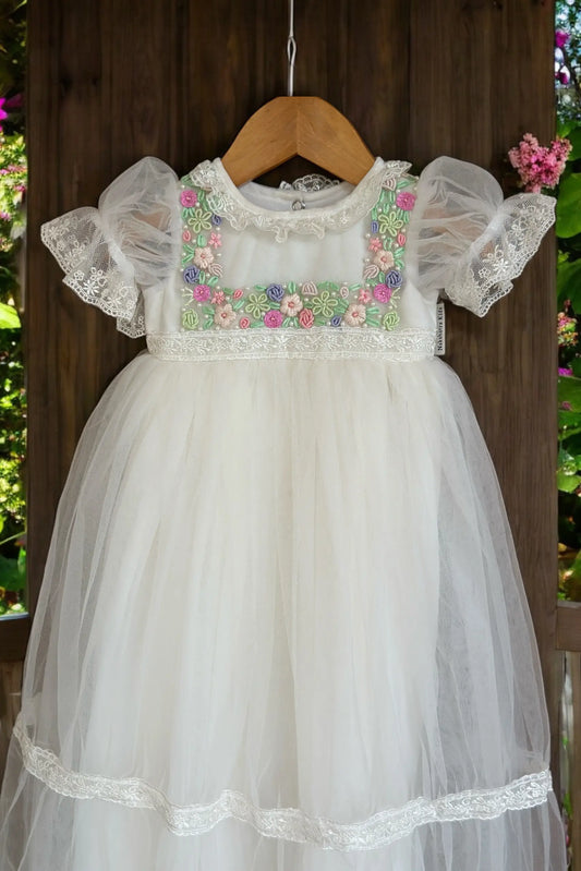 Close-up of premium pearl accents and fine hand-embroidery on a boutique off-white christening frock