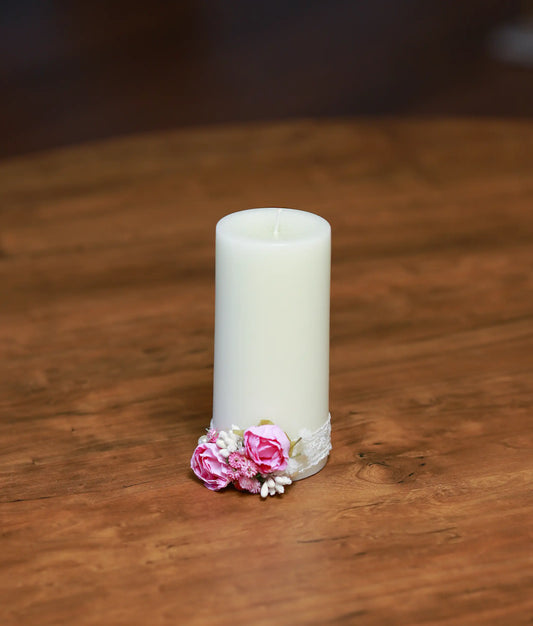 Front view of a white baptism candle decorated with soft pink roses, white flowers, and a pink satin ribbon