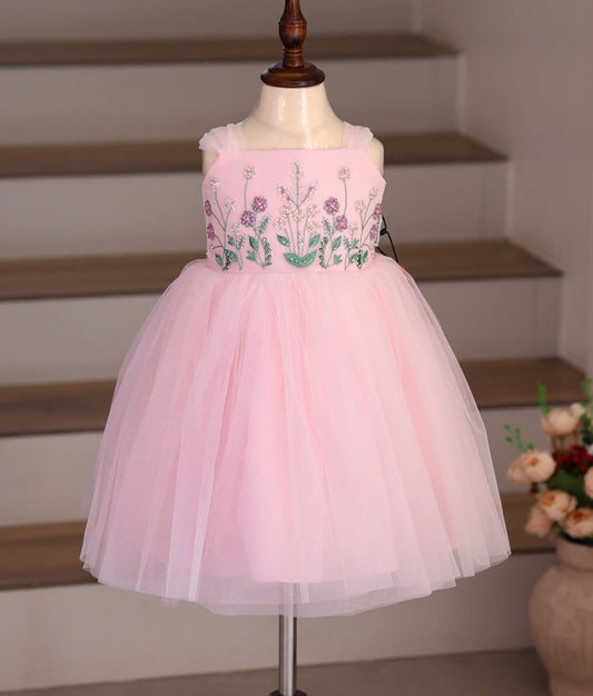 Front view of a pink tulle net frock with handworked detailing on the top.