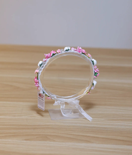 Front view of a pink and white floral tiara for baby girls featuring delicate blossoms and a lace-wrapped band