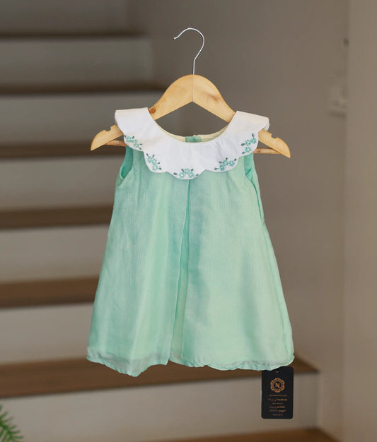 Full front view of a pista green crush georgette A-line frock for girls featuring a continuous white scalloped cape collar.