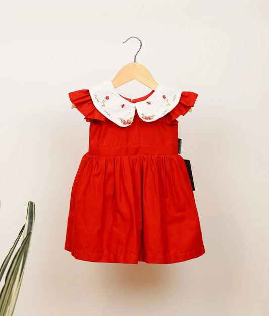Red cotton frock with cap sleeves, plain yoke, and embroidered Peter Pan collar for baby girls.