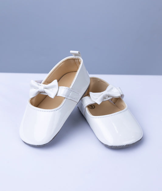 Elegant white baptism shoes for baby girls with delicate pearl accents and soft lace detailing.