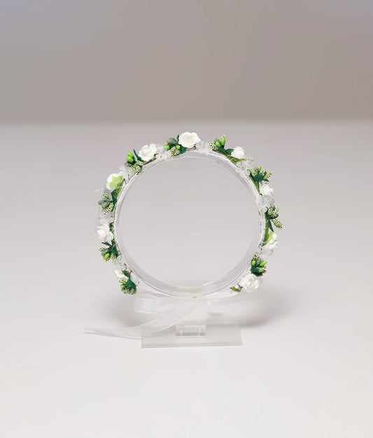 Front view of a white and green floral handmade tiara for girls with white roses and organza ribbon
