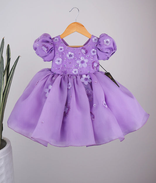 Front view of handworked flower-themed baby girl dress against white background