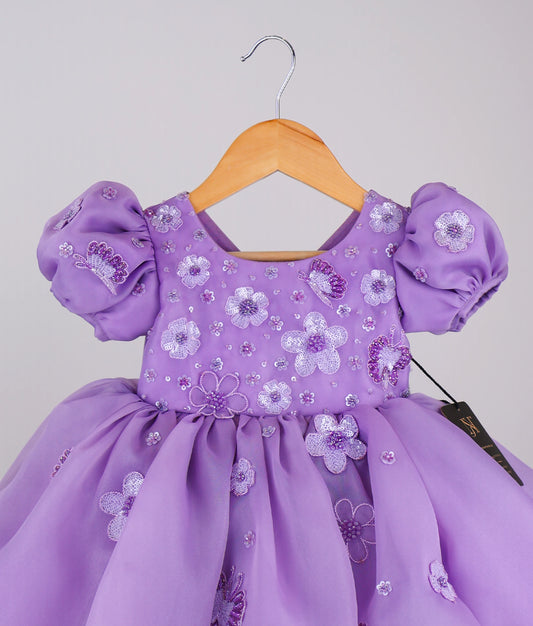 Close view of handworked flower-themed baby girl dress against white background