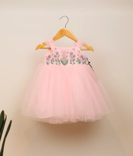 Front view of pink tulle net floral handworked birthday frock against plain background