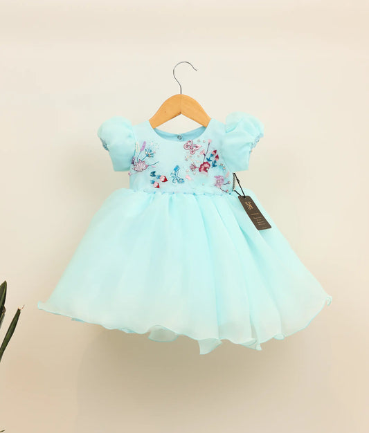 Front view of sky blue plain organza birthday frock aginst plain background