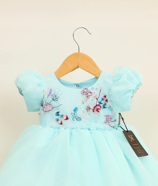 Close view of sky blue plain organza birthday frock against plain background