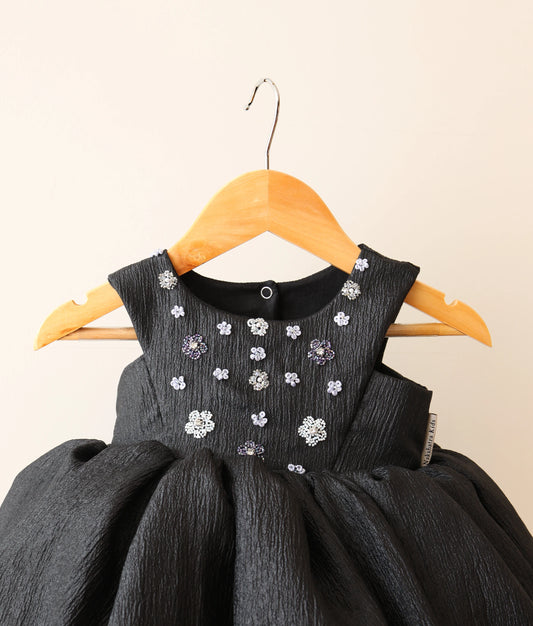 Close view of black crush organza floral handworked birthday frock against plain background