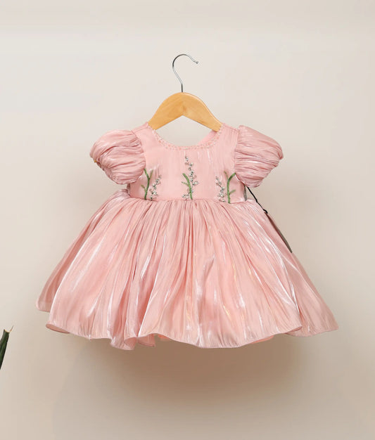 Front view of peach lacer organza floral handworked birthday frock against plain background
