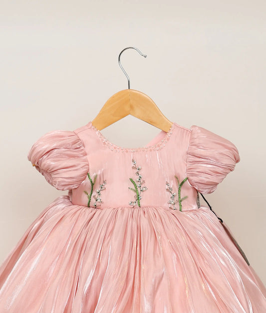 Close view of peach lacer organza floral handworked birthday frock against plain background