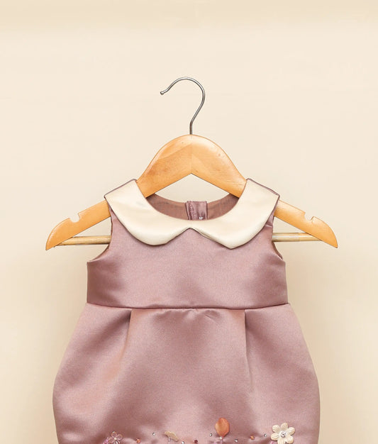 Close view of a pastel lavender handworked fish-cut frock against plain ground
